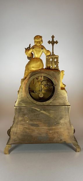 null Pendule en bronze doré surmontée d'une femme au calvaire, décors de rinceaux...
