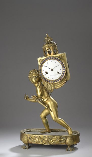 null A gilt bronze clock with a love figure on its back, topped by a cage decorated...