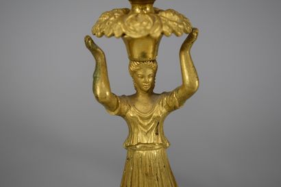 null A pair of bronze candlesticks representing a caryatid supporting a flowered...