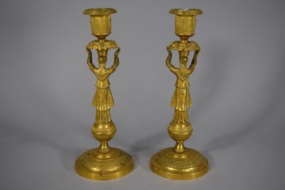 null A pair of bronze candlesticks representing a caryatid supporting a flowered...