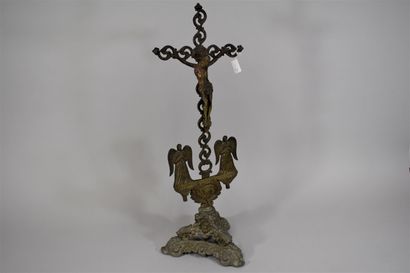 null Bronze crucifix, two angels and a lamb at its base, it rests on a tripod support...