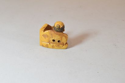 null Tinted netsuke showing a character holding a plate engraved with calligraphy



H....
