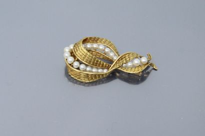  Broche « nœud » en or jaune 18K (750) texturé et amati, serti d'une ligne de perles...