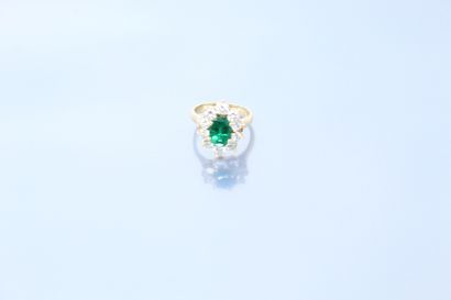 null An 18K (750) yellow gold daisy ring set with an oval emerald in a diamond setting....