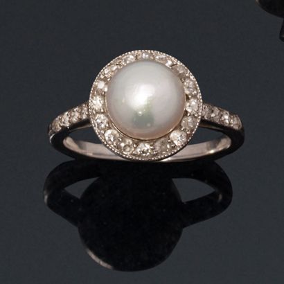 null An 18K (750) white gold ring centered on a fine button pearl surrounded and...