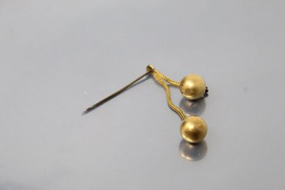 null Epingle formée de deux chaînes terminées chacune par une sphère d'or 18K (750)....