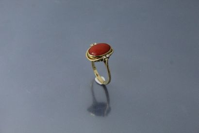 null 18k (750) yellow gold ring set with a coral cabochon with two diamonds on either...