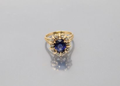 null 18k (750) yellow gold ring holding an oval synthetic sapphire in a brilliant-cut...