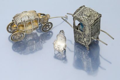 null Three objects in the display case :

- filigree metal carriage. L. : 7.50 cm.

-...