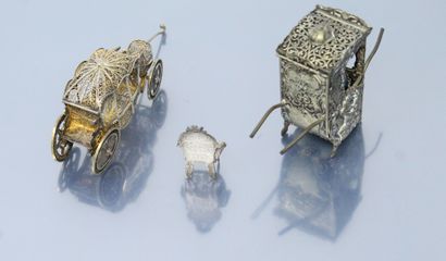 null Three objects in the display case :

- filigree metal carriage. L. : 7.50 cm.

-...