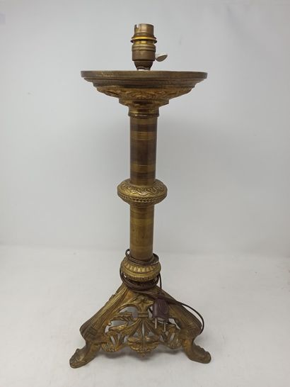 null Bronze candlestick with cylindrical shaft resting on a tripod base decorated...
