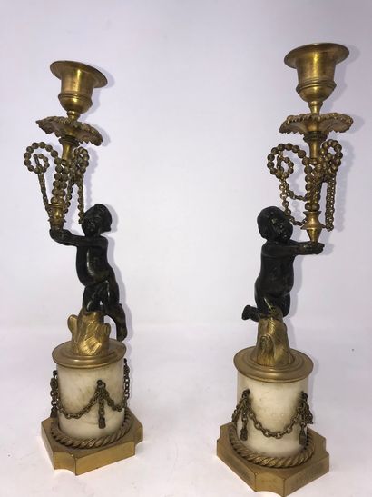 null 
A pair of candlesticks decorated with cherubs in black patina bronze.

Marble...