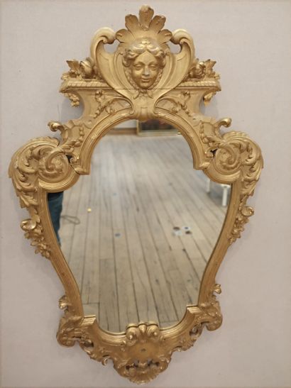 null A carved and gilded wood mirror with a mascaron and a cherub head.

Regency...