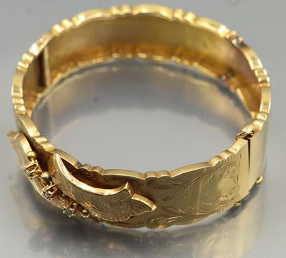 null Bracelet rigide ouvrant en or jaune 18K (750) à décor de rinceaux et feuillages...