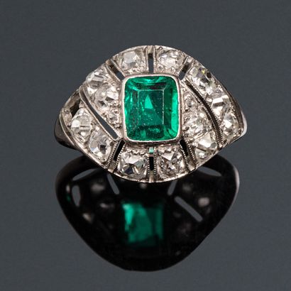 null A platinum ring set with an emerald in an openwork setting of old cut diamonds....