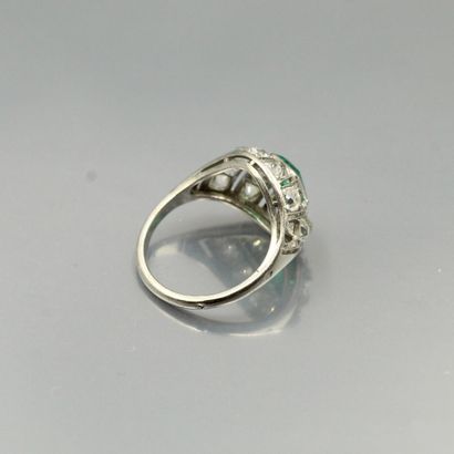 null A platinum ring set with an emerald in an openwork setting of old cut diamonds....