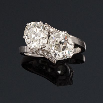 null A platinum ring set with two cushion-cut diamonds and ten old-cut diamonds.

Mascaron...