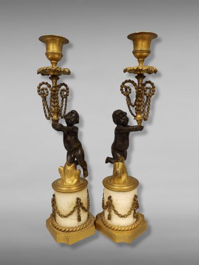 A pair of candlesticks decorated with cherubs...