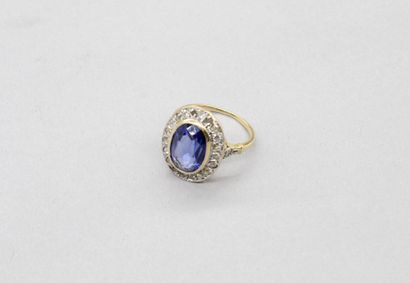 null 18K (750) yellow gold ring set with an oval sapphire in a closed setting surrounded...