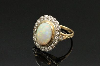 null 18K (750) gold ring, set with a cabochon opal surrounded and shouldered by round...