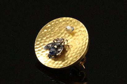 null Round brooch in 18K (750) gold, decorated with a silver fly, the body in sapphire,...