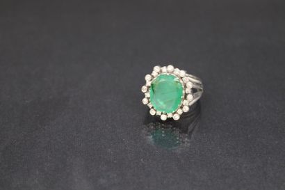 null Bague en or gris 18K (750) ornée d'une émeraude ovale dans un entourage de diamants....