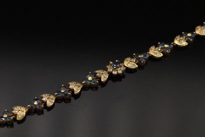 null 
Bracelet en or 18K (750), articulé de fleurettes serties de saphirs et de feuilles...