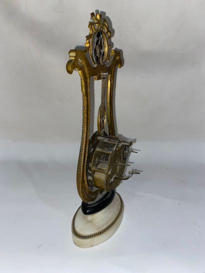 null Petite pendule de chambre en forme de lyre en bronze sculpté et doré et à décor...