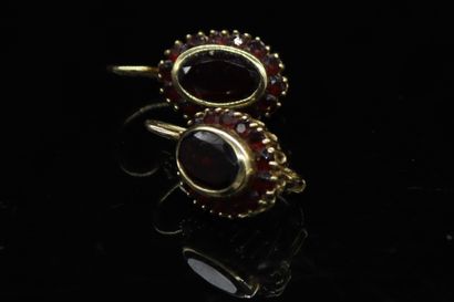 null Pair of 18k (750) yellow gold earrings, each set with an oval garnet in a circle...