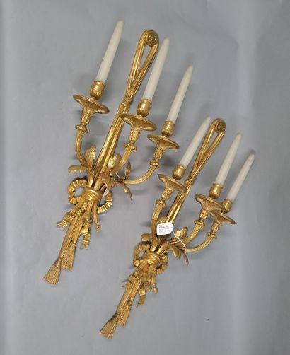 null Pair of gilt bronze sconces depicting a long knotted ribbon holding three leafy...