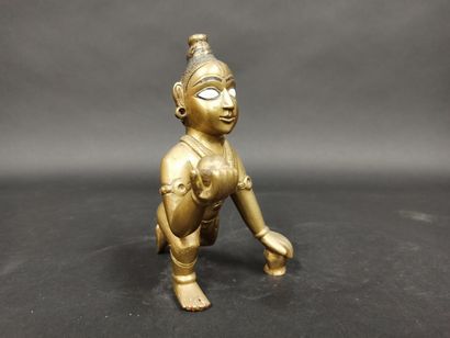 Statuette de bouddha enfant à la motte de beurre en alliage de bronze et pigments, les yeux incrustés.