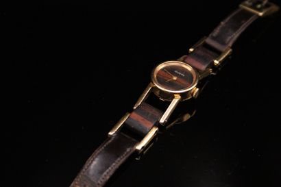null GUCCI
Circa 1970

Rare montre bracelet de femme en or 750°, bois et cuir brun....