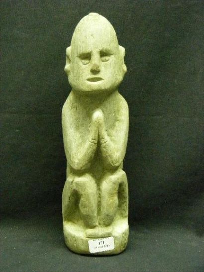 null Sculpture en pierre grise représentant un personnage assis, les mains jointes....