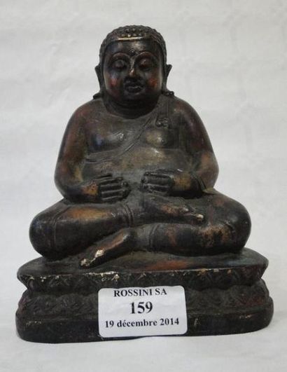 null Bouddha en bronze représenté les mains sur le ventre assis sur une base lotiforme....