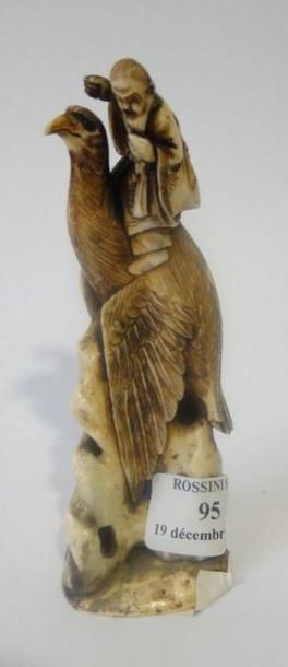 null Okimono en ivoire teinté représentant un oiseau mythique posé sur une roche...