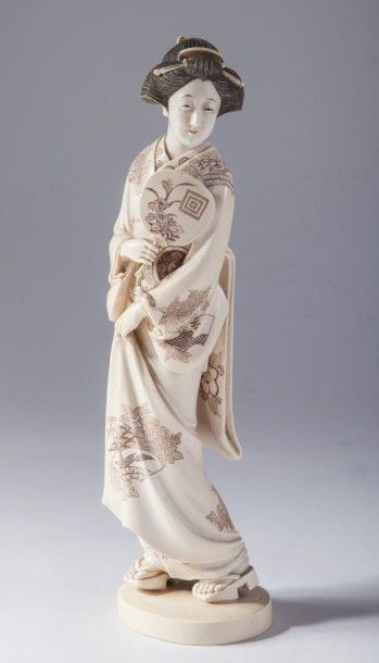 null Geisha en ivoire tenant un utchiwa dans la main droite au vêtement orné de motifs...