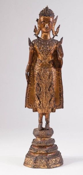 null Bouddha en bronze laqué or représenté debout sur un haut socle, la main gauche...