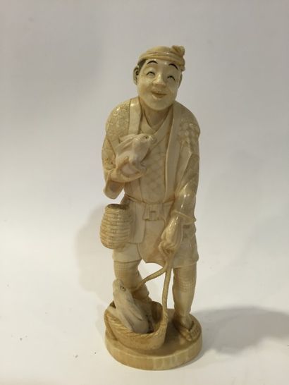 null Okimono en ivoire sculpté représentant un homme portant deux lapins. 

Japon,...