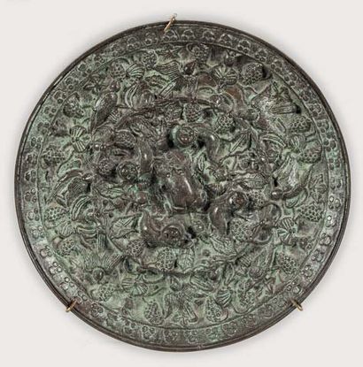 ASIE Important miroir en bronze de patine verte, à décor en relief de loirs et oiseaux...