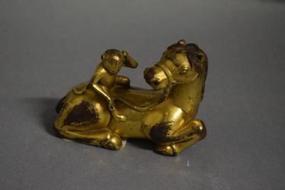 null Sujet en bronze doré représentant un cheval couché, la tête vers l'arrière,...