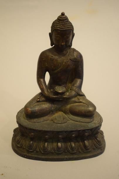 null Buddha en bronze à patine brune assis en méditation , tenant un bol à aumones.

CHINE,...