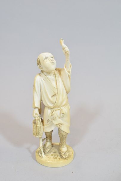 null Okimono en ivoire sculpté représentant un homme portant un panier et brandissant...