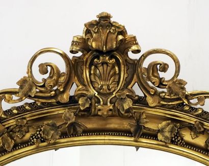 null Miroir mural style Louis XV en bois doré richement décroé de guirlandes de fleurs,...