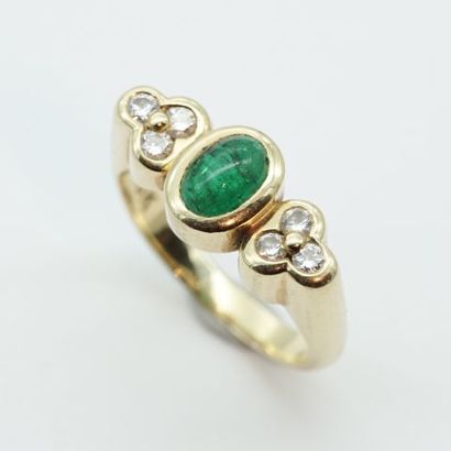 null An 18K yellow gold ring with a cabochon emerald set with a trio of diamonds...