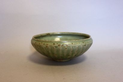null A celadon glazed earthenware bowl with a crackled effect resting on a wooden...