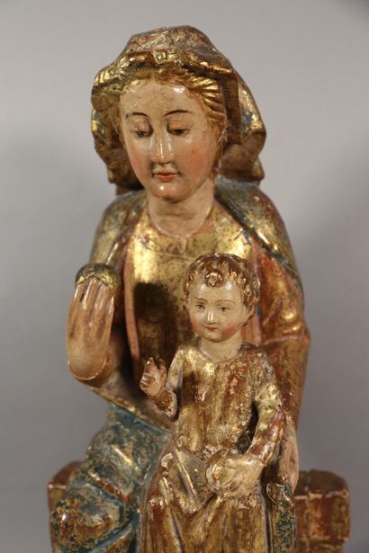 null Vierge à l'Enfant en bois sculpté, polychromé et doré. Assise sur un banc trône,...