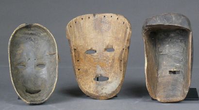 null Trois masques en bois à patine sombre : l'un en bois léger, les yeux soulignés...