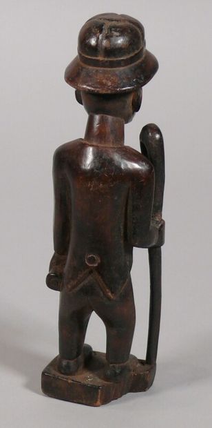 null Colon statuette in hardwood with dark patina showing a male figure wearing a...