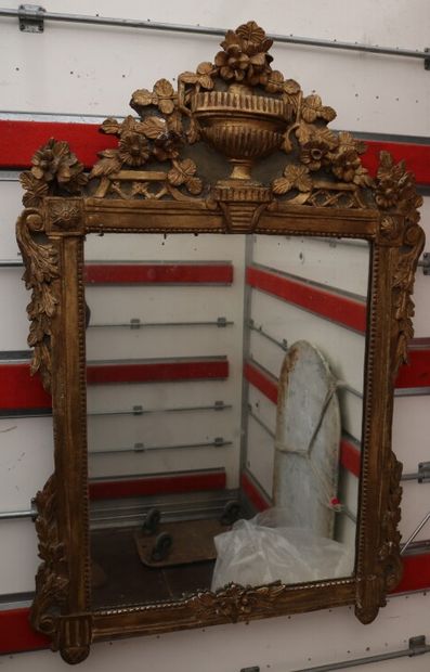 null A mirror, the frame in wood and gilded stucco, the pediment decorated with a...