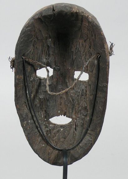 null Hardwood mask with a dark patina of use depicting a geometrical oval face with...